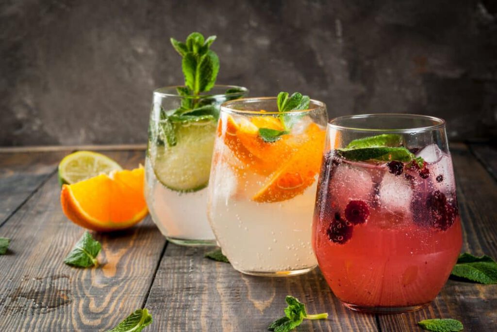Three glasses of cocktails with different garnishes