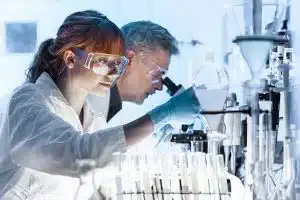 Scientists in Lab wearing glasses looking through microscope